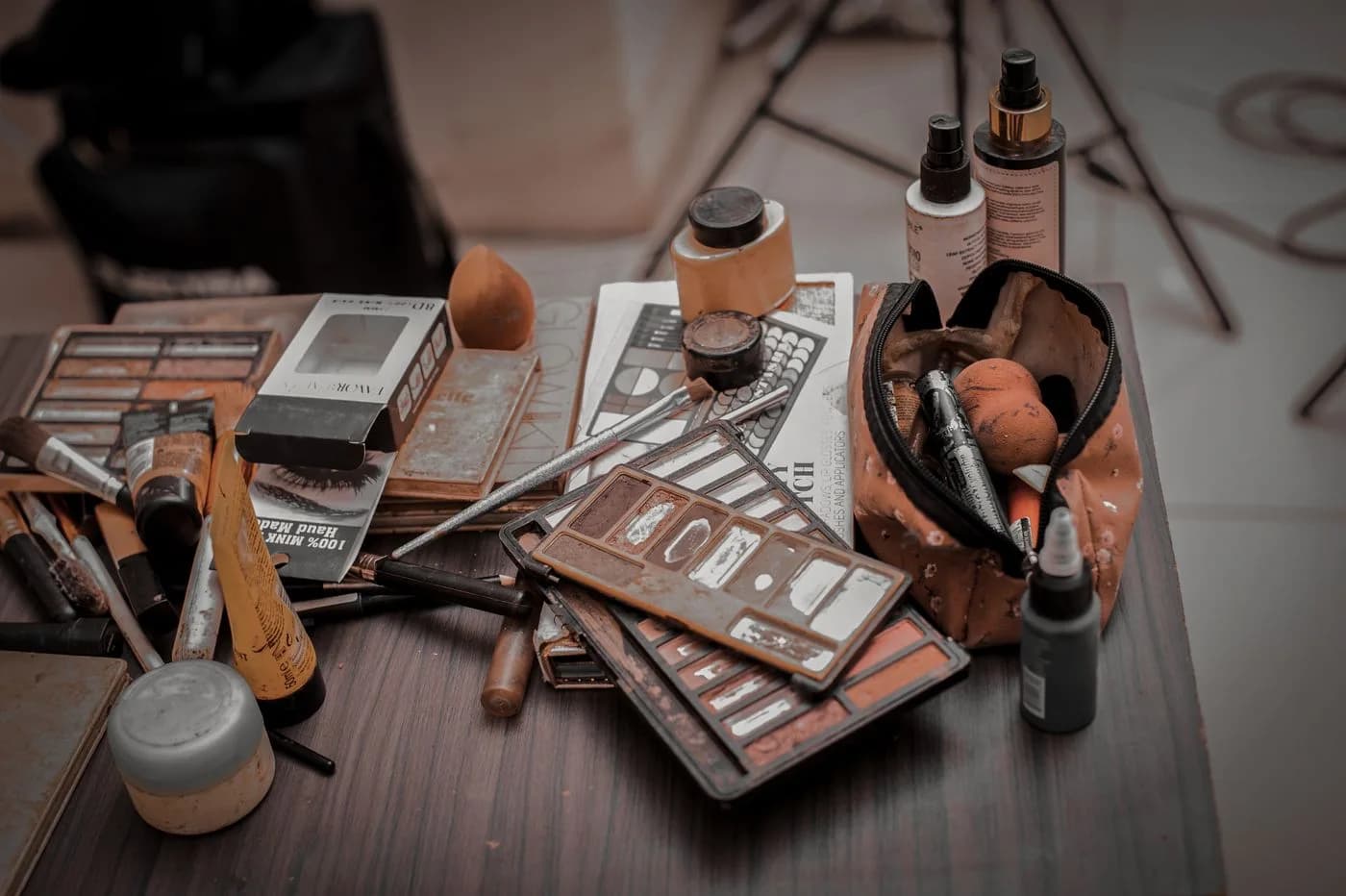 Used makeup palettes, brushes and bottles on a working table