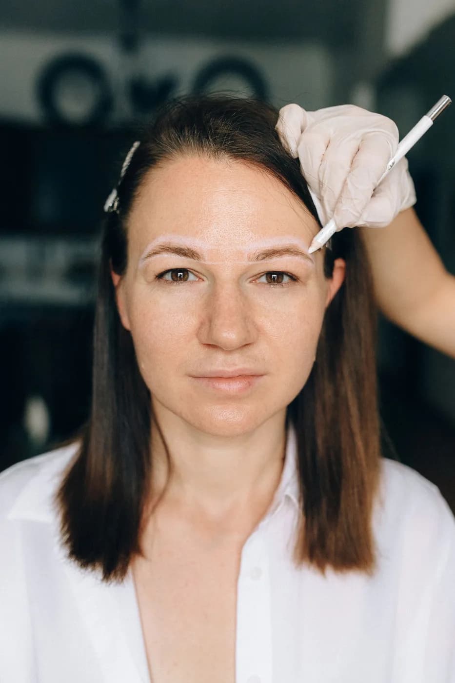 A practitioner carefully marking a client’s eyebrow shape